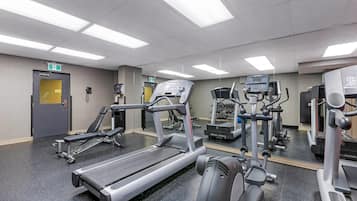 Un gimnasio con cintas de correr, máquinas de pesas y un espejo grande.