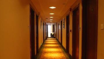 A hotel hallway with carpeted floors, wooden doors, and recessed lighting.
