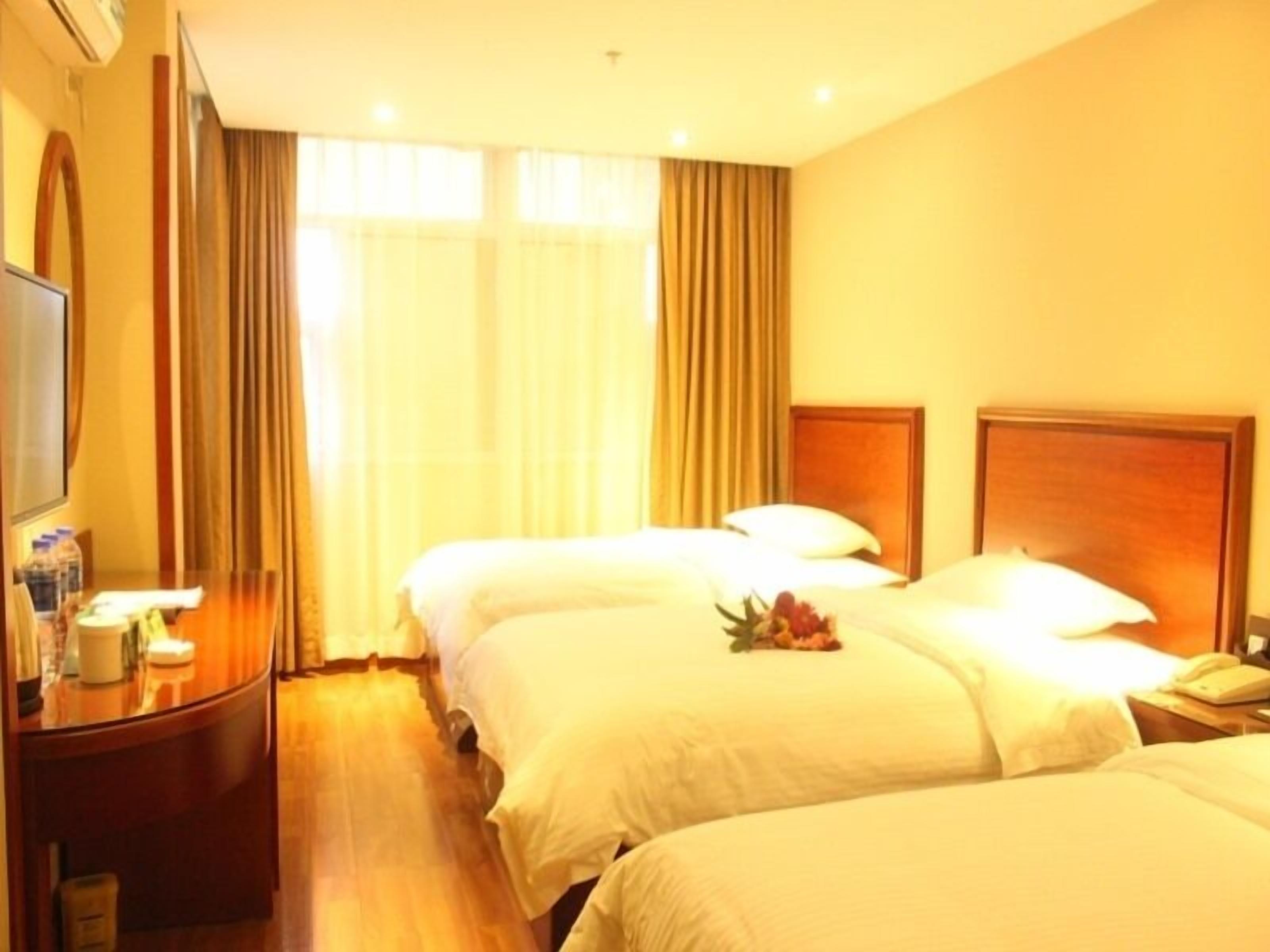 A hotel room with two beds, a desk, and a TV.