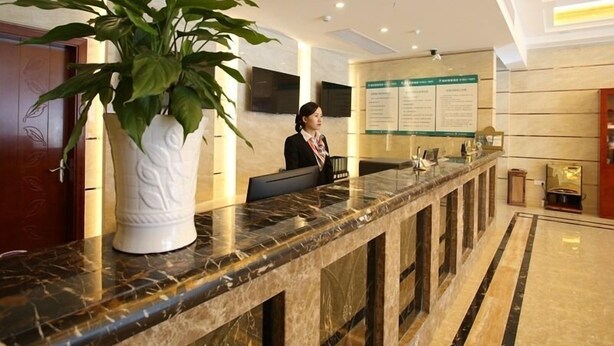 A reception desk with a large potted plant, a marble counter, and a wall-mounted information board. - GreenTree Inn KunShan Lujia Town Furong Road Express Hotel (Suzhou)