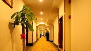 A hotel hallway with a carpeted floor, a potted plant, and doors on both sides. - GreenTree Inn KunShan Lujia Town Furong Road Express Hotel (Suzhou)