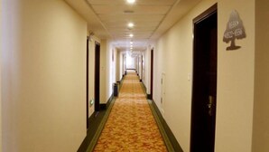 Un largo y estrecho pasillo de hotel con puertas a ambos lados y suelo cubierto de alfombra.