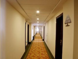 Un largo y estrecho pasillo de hotel con puertas a ambos lados y suelo cubierto de alfombra.