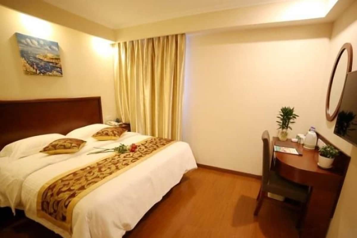 Habitación de hotel con cama, escritorio, silla, espejo y un cuadro en la pared.