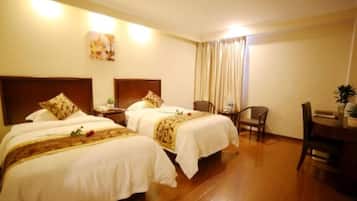 A hotel room with two beds, a desk, and a chair.