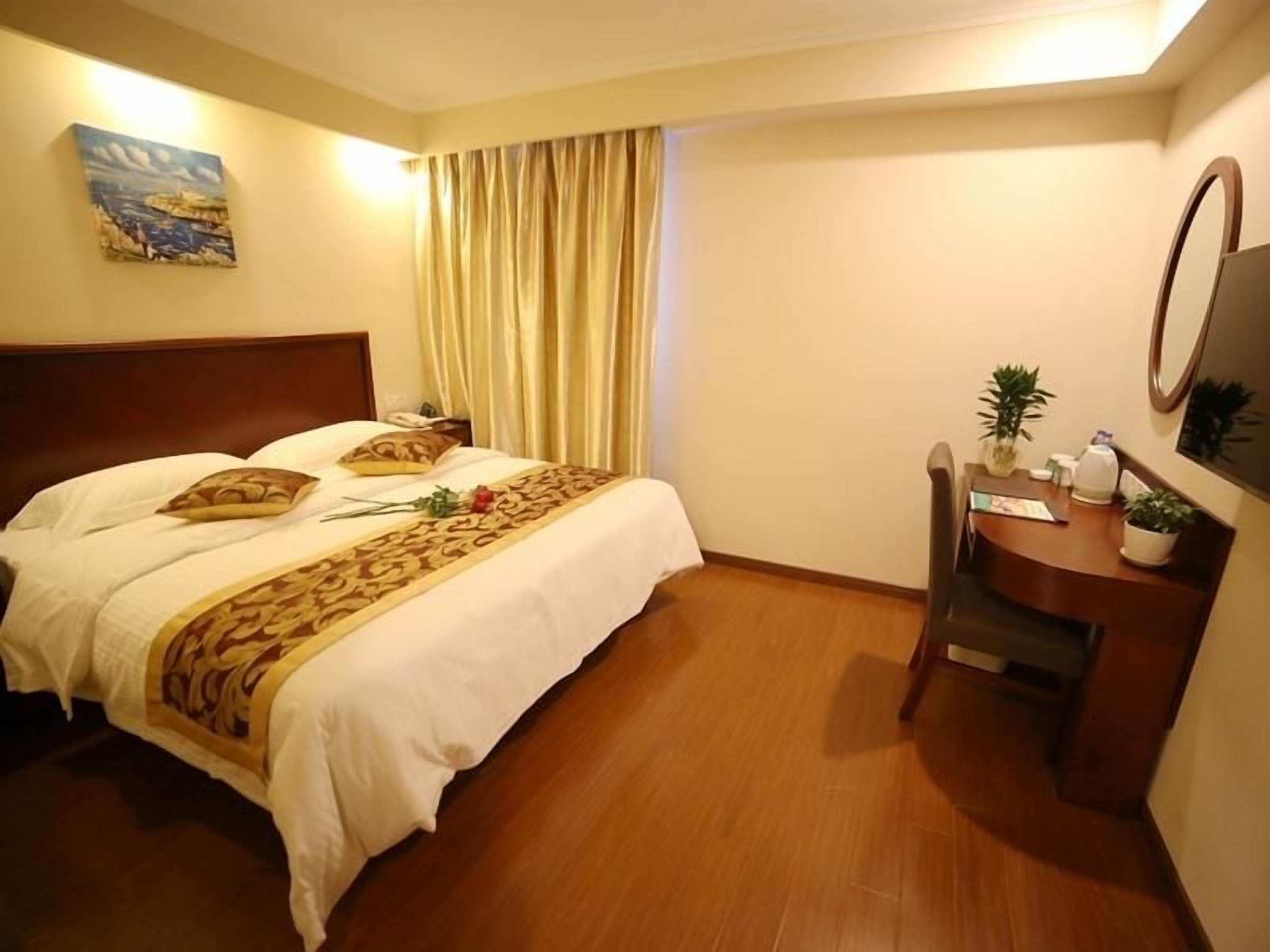 A hotel room with a bed, a desk, a chair, a mirror, and a window with curtains.