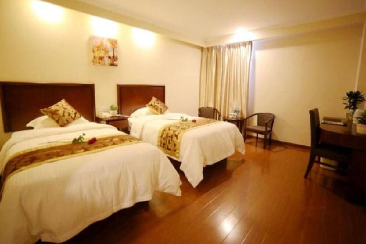 Habitació d'hotel amb dos llits, una escriptori, una cadira i una taula de dinar.