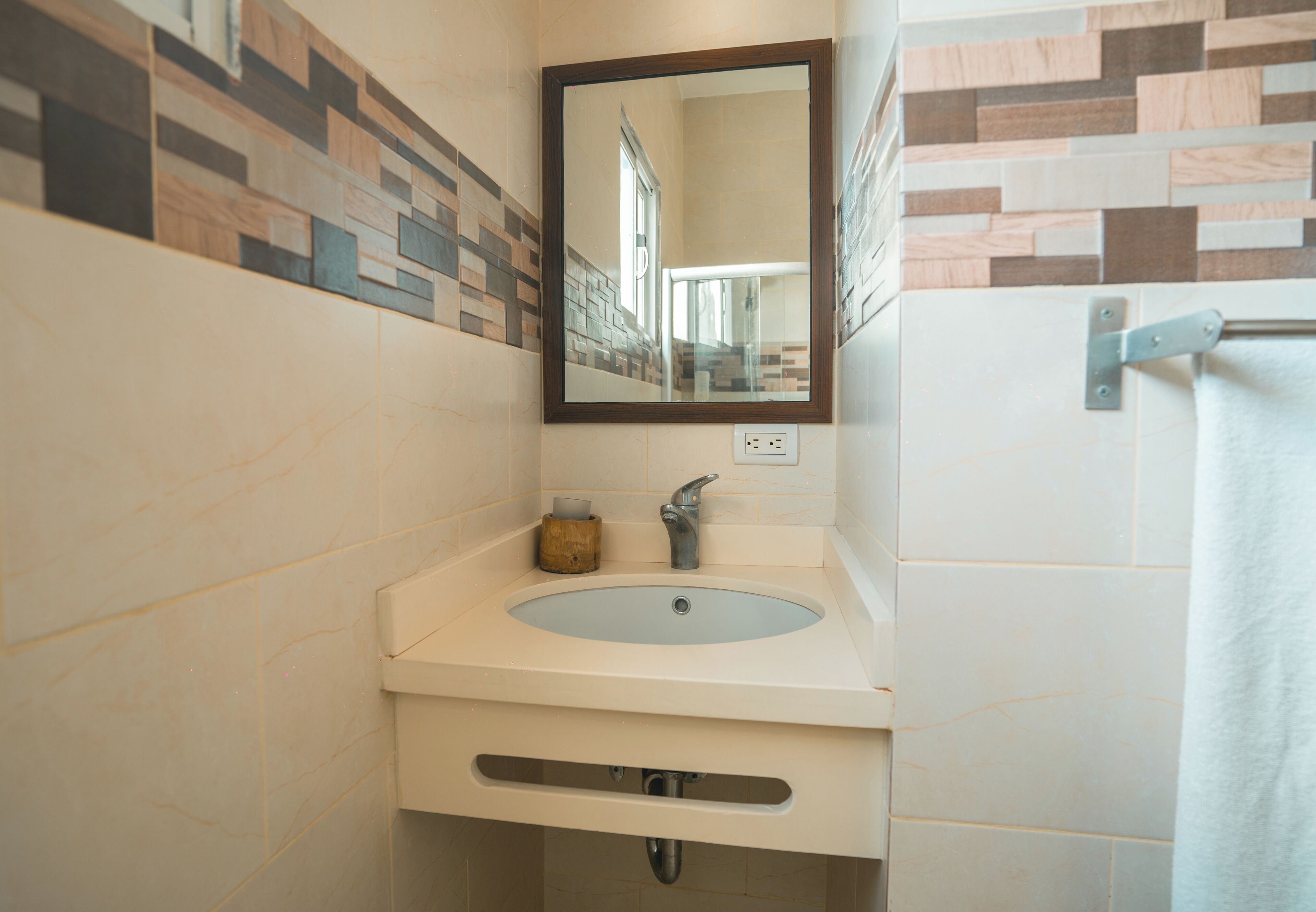 A bathroom with a sink, mirror, and towel rack.