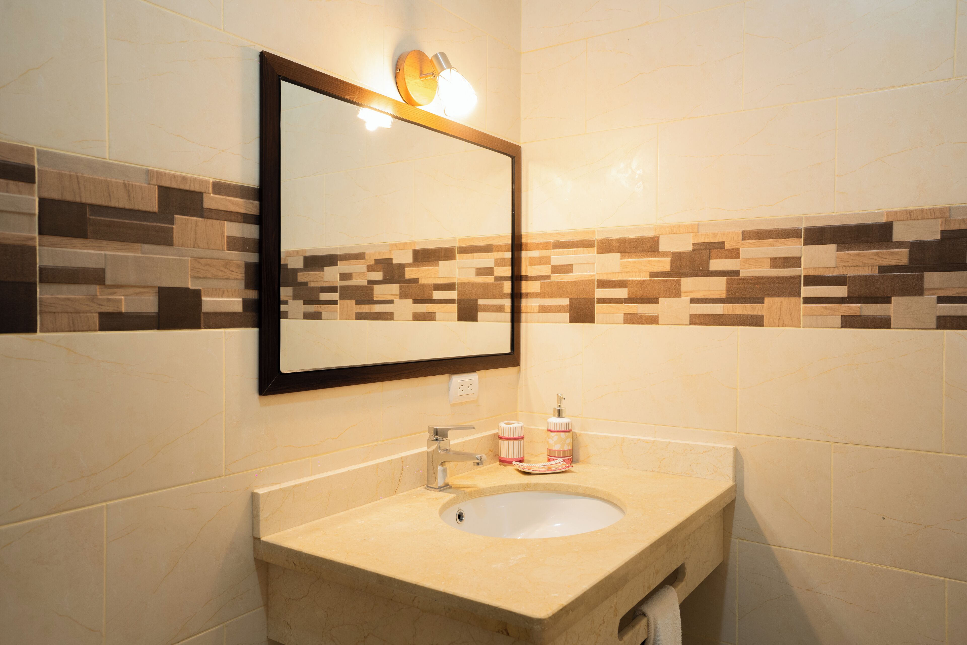 A bathroom with a sink, mirror, and tiled walls.