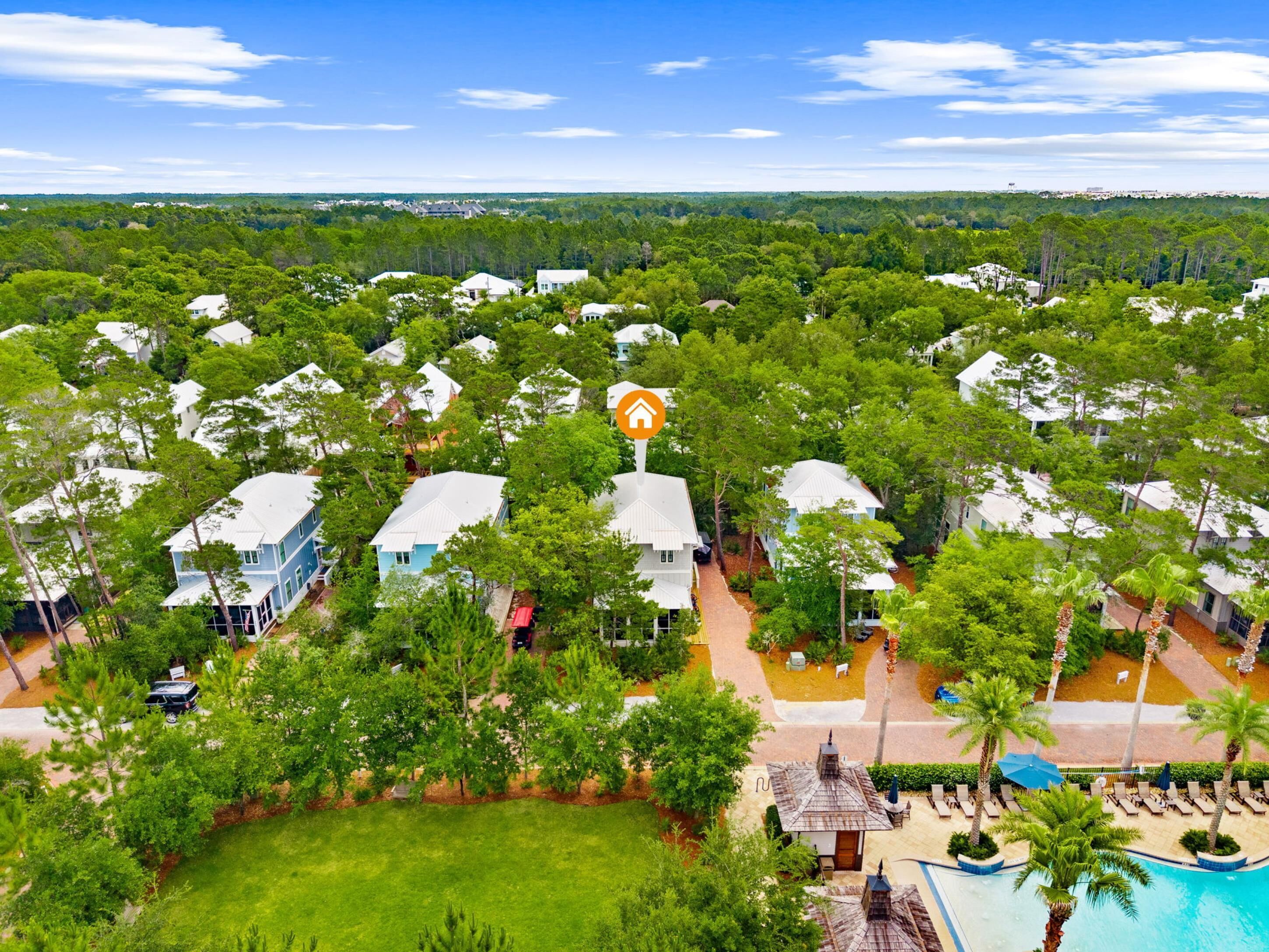 A resort with multiple white buildings surrounded by lush greenery, a swimming pool, and a clear blue sky.