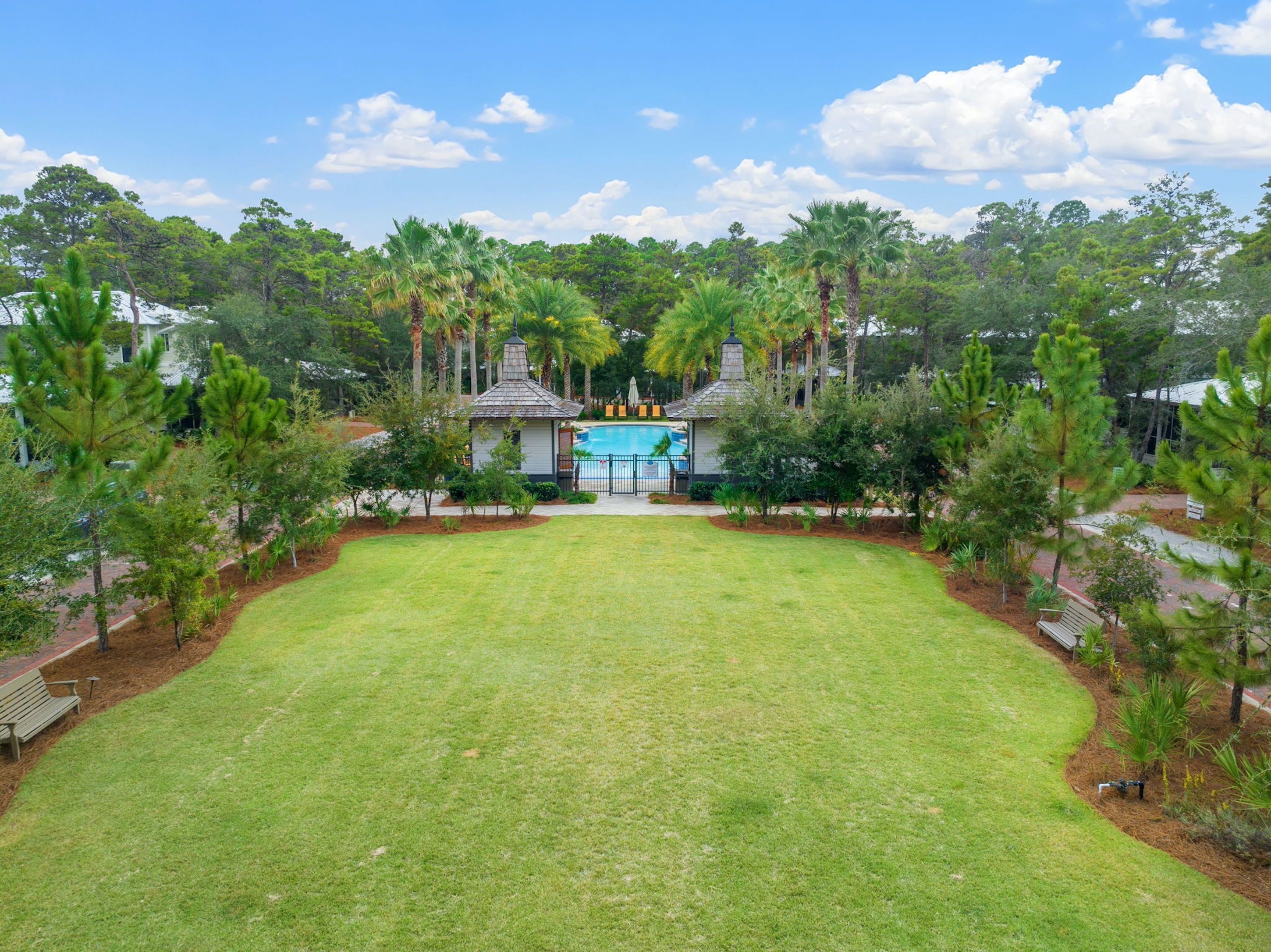 A large, well-maintained lawn with a pool and a gazebo in the center.