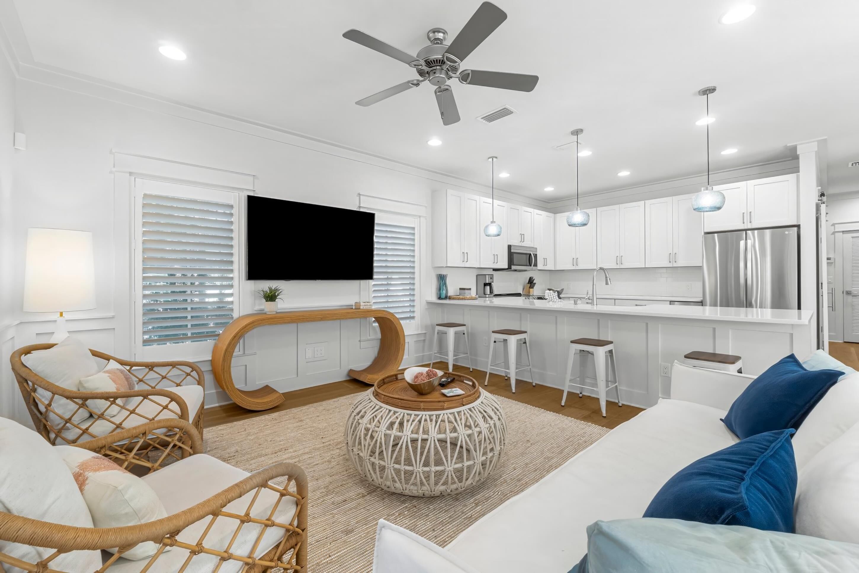 A modern living room with a sofa, a round coffee table, and wicker chairs.