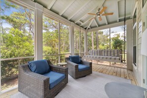 A covered porch with wicker furniture and a ceiling fan. - Magnolia Cottages by the Sea by Panhandle Getaways (Panama City Beach)