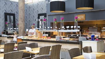 Un restaurant avec des chaises en osier, un comptoir où sont exposés des plats, et une enseigne indiquant « SERVICE ».
