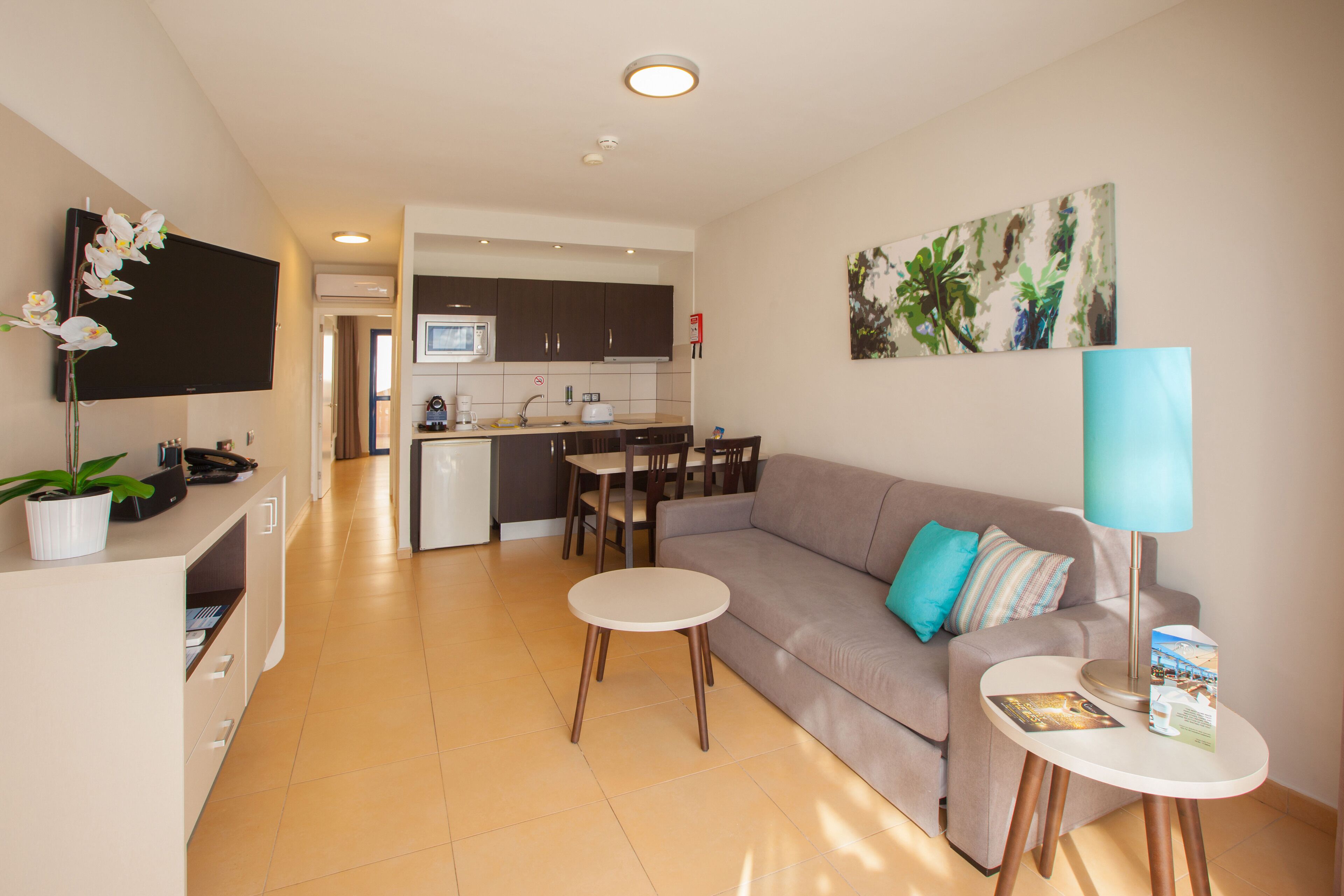 A modern living room with a sofa, coffee table, and a dining area with chairs and a table.