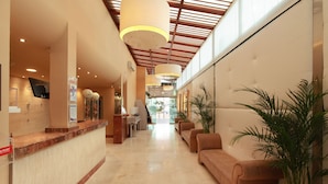 En hotellobby med en receptionsdisk, en sittgrupp och ett stort fönster.