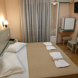 A hotel room with a bed, a bedside table, a TV, a chair, and a small table with a mirror.