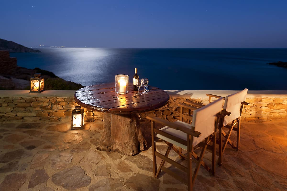 Un espacio para comer al aire libre con una mesa redonda, sillas y una vela.