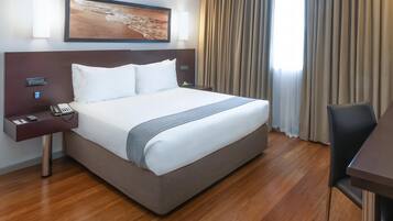 A hotel room with a large bed, a desk, and a chair.