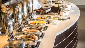 A buffet setup with multiple serving dishes and a person in the background. - Garden Court Kings Beach (Gqeberha (Port Elizabeth))