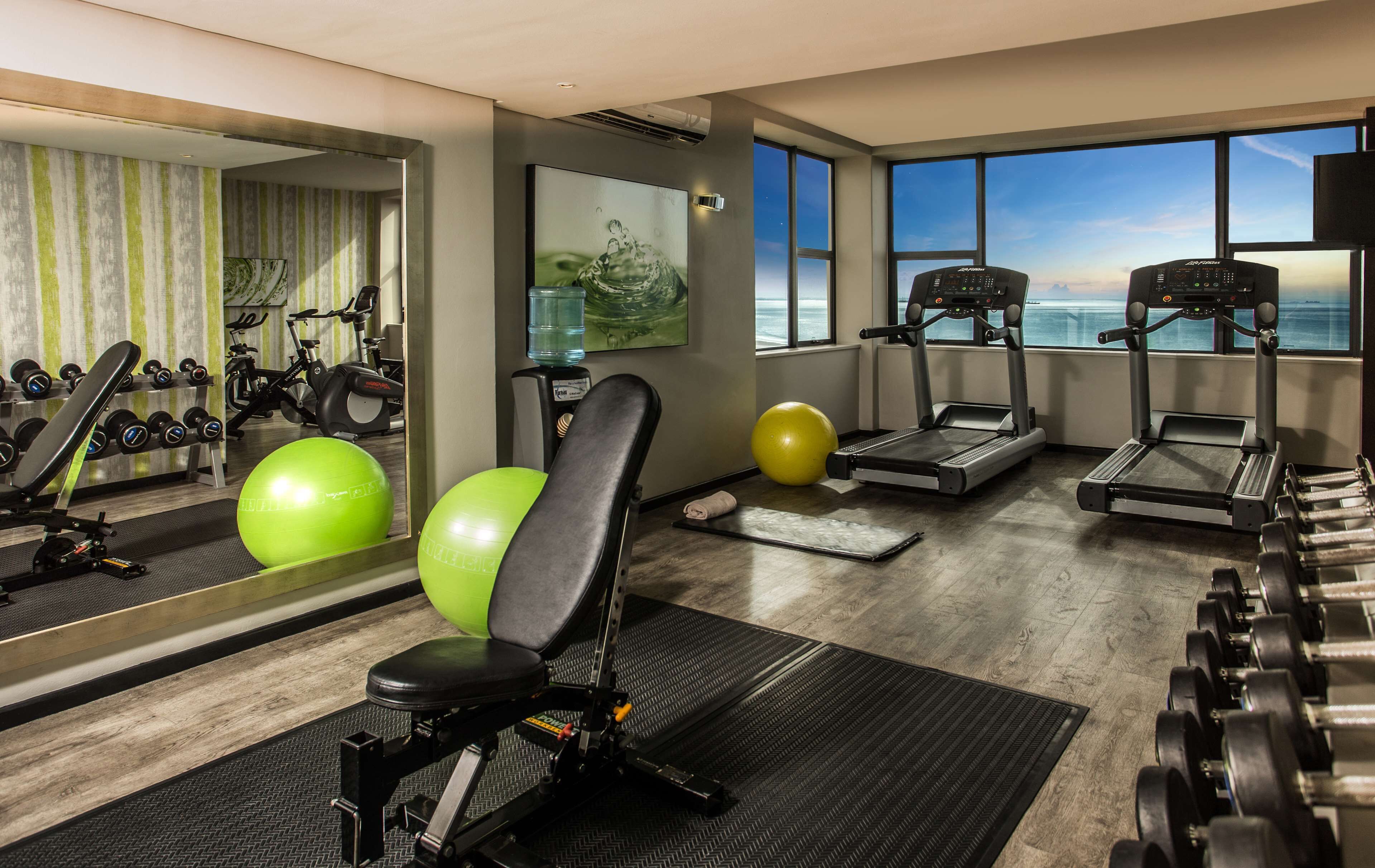 A gym with treadmills, exercise balls, and dumbbells.