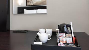 A hotel room with a tray containing a teapot, two cups, and a kettle.