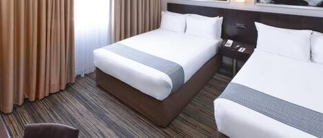 A hotel room with two beds, a desk, and a view of the ocean.