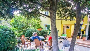 An outdoor patio with wicker chairs and tables, surrounded by greenery and trees. - Apartments Irena (Zadar)