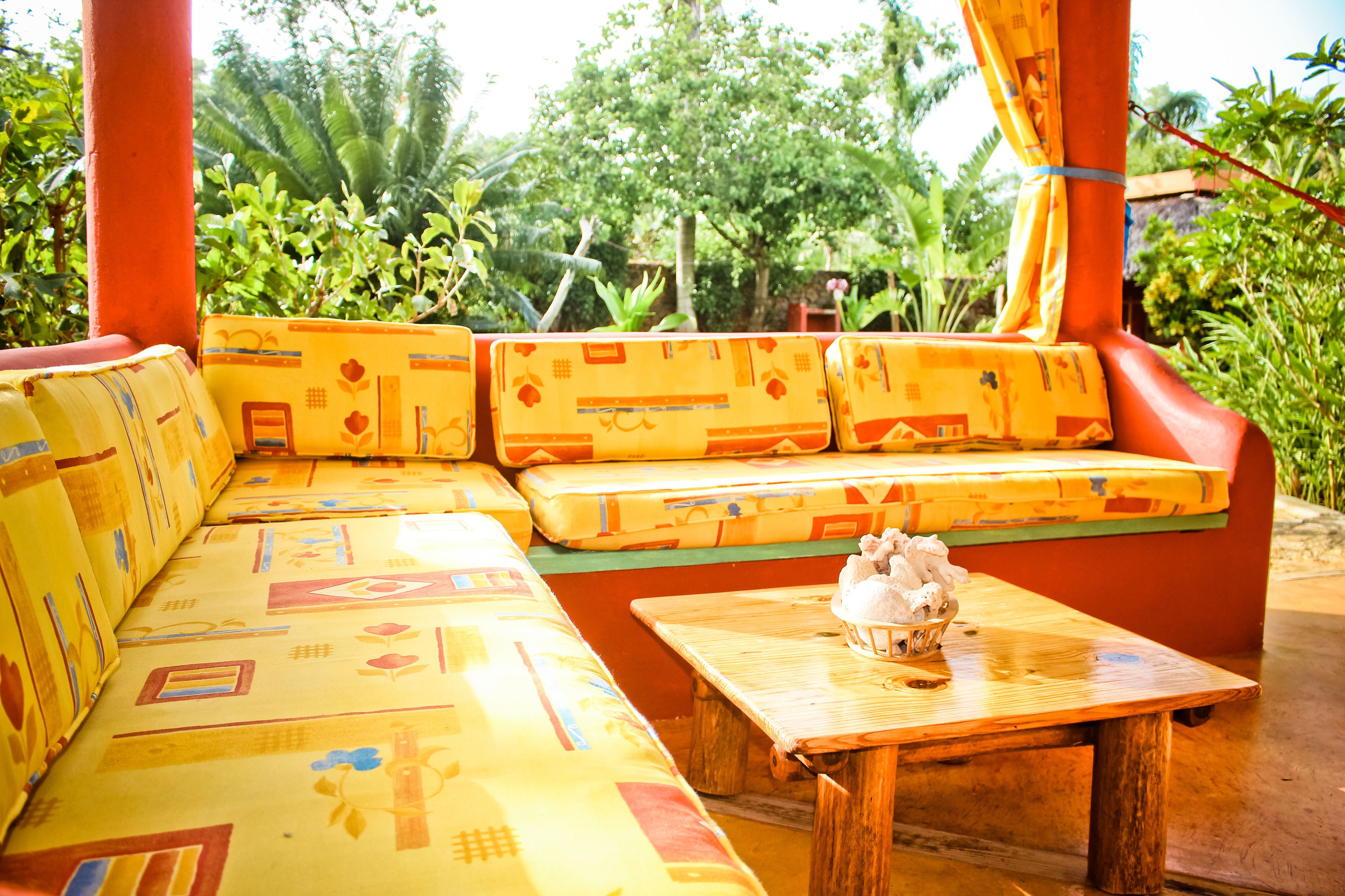 A wooden bench with a cushion, a small table with a decorative item, and a colorful patterned sofa.