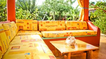 A wooden bench with a cushion, a small table with a decorative item, and a colorful patterned sofa.