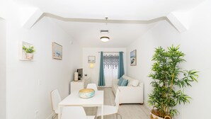 A modern, well-lit room with a dining area, a sofa, and a large potted plant. - 335 Ocean Walk Apartments (Miami Beach)