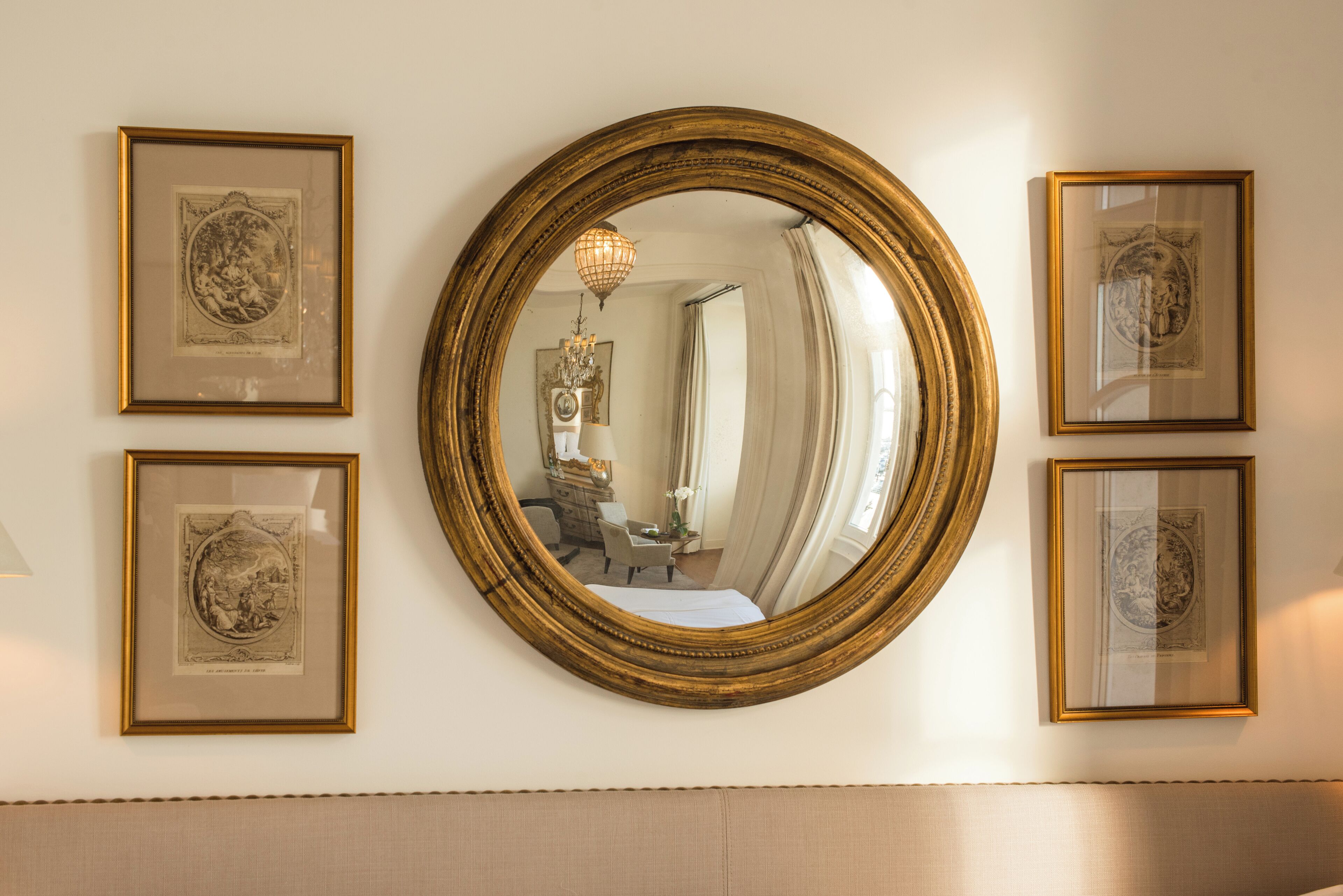 A wall with a large mirror surrounded by framed artwork.
