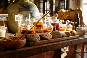 A breakfast buffet with various food items and condiments, including jars of honey and jams, and a wooden board with labeled rocks. - Bordoy Grand House Algarve (Vila Real Santo Antonio)