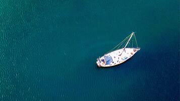 An aerial view of a sailboat on calm, turquoise water.