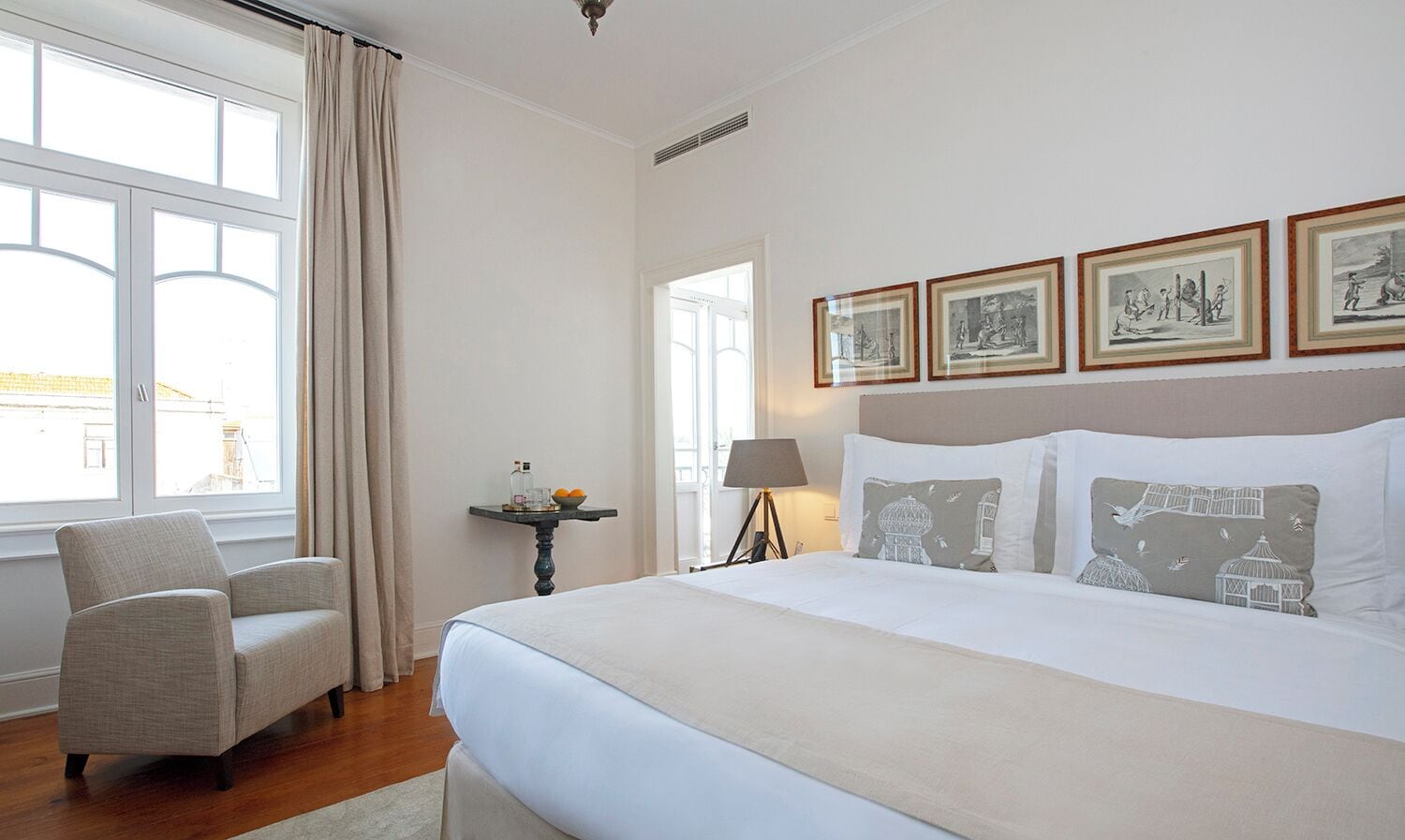 Une chambre d’hôtel avec un grand lit, une chaise, une table de chevet avec une lampe et des tableaux encadrés au mur.
