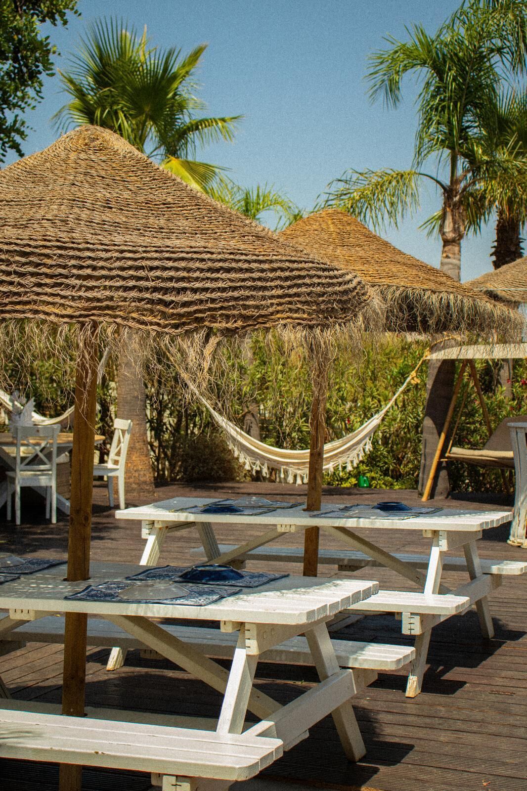 Outdoor seating areas with thatched umbrellas and wooden tables.