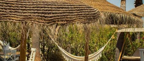 Outdoor seating areas with thatched umbrellas and wooden tables.