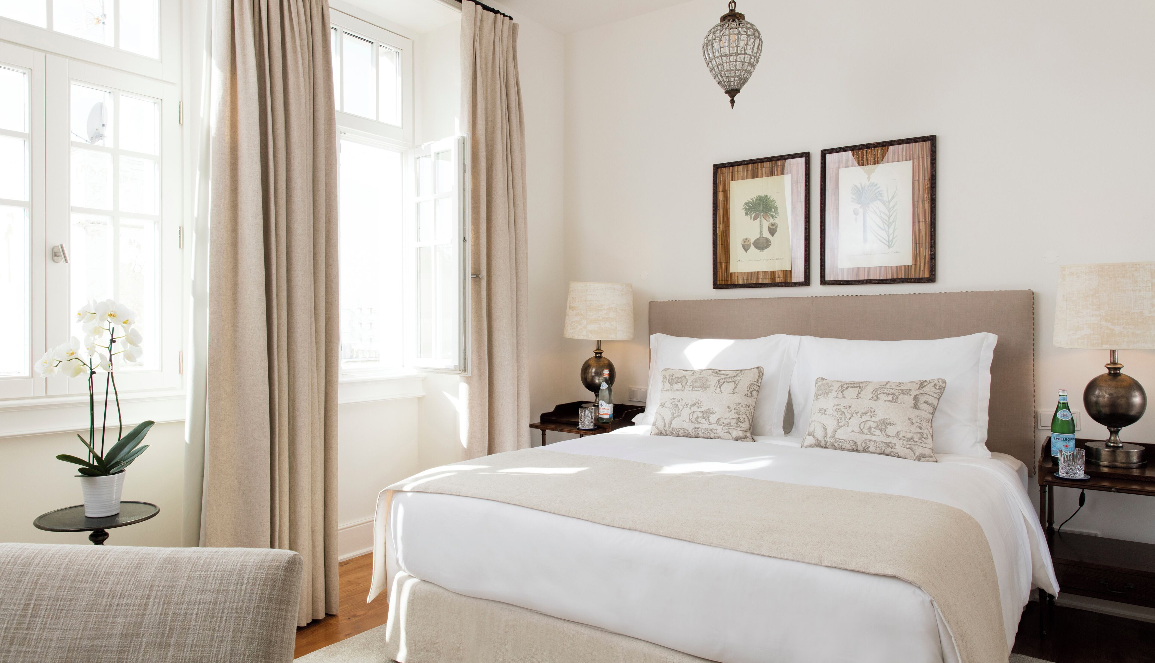 Ein Hotelzimmer mit einem großen Bett, zwei Nachttischen, einer Kandelaber und zwei gerahmten Bildern an der Wand.