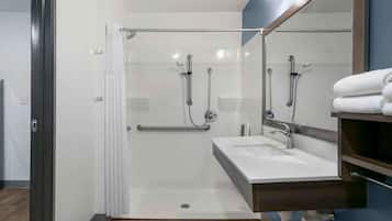 A modern bathroom with a glass shower enclosure, a white sink, and a large mirror.