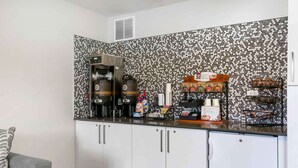 A kitchenette with a coffee machine, a refrigerator, and various food items on the counter. - Extended Stay America Suites - Providence (Providence)