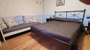 Un dormitorio con una cama, una mesita de noche, una lámpara y un cuadro colgado en la pared.