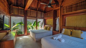 Quarto de madeira com duas camas, um ventilador de teto e uma televisão.