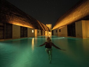 A person walking in a pool area with a night sky visible above. - Punta Caliza (Isla Holbox)