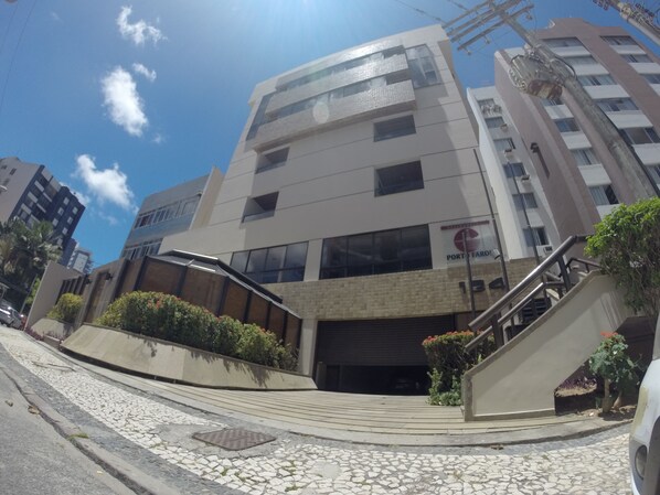 A multi-story building with a modern architectural design, featuring a mix of glass and brick facades, and a visible entrance with a staircase.
