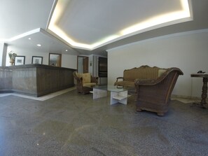 A lobby with a reception desk, two sofas, a coffee table, and a small table with a lamp.