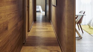 A wooden hallway with a modern design, leading to a room with a bed and a chair. - Felix Luxury Plus by Viadora (Mexico City)