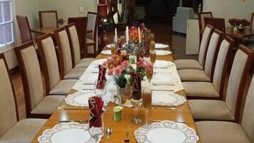 Un comedor con una larga mesa de madera dispuesta para una comida, rodeado de sillas tapizadas.