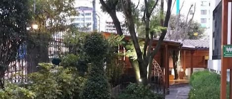 Un sendero en un jardín con pavimento de piedra, rodeado de arbustos y árboles.