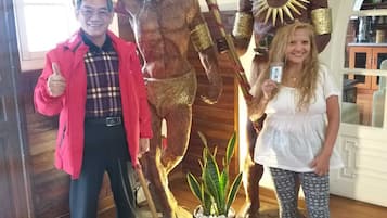 Et værelse med trægulv, en potteplante og en statue af en figur med en stav.