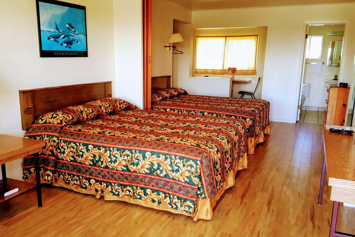 A bedroom with a large bed, a desk, a chair, and a TV.